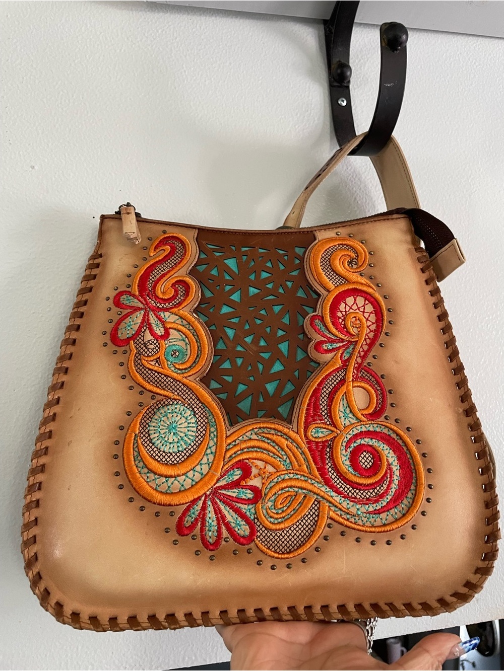 Artisan structured leather handbag features intricate floral embroidery